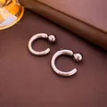 Dettaglio di orecchini geometrici a C in argento con sfere metalliche lucide - Argento