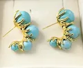 Macro shot of minimalist gold studs featuring turquoise beads in a vintage C-shape design - Turquoise Earring Style (WXE3887YL)