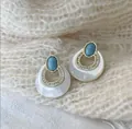 Detail of vintage round turquoise earrings with gold rim on white knit background - Teardrop Shell Style (WXE4267Y)