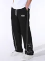 Close-up detail of men's black sports pants with white side stripes and star embroidery. - Black