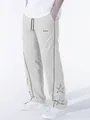Macro view of men's gray high street sports trousers with star embroidery and brown stripes - Beige