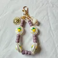 Portachiavi artigianale con perle viola e bianche, motivi a fragola, sole e conchiglia - Ciondolo Sole e Conchiglia