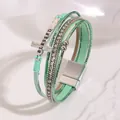 Close-up of bohemian multilayer leather bracelet with cross and BLESSED engraving - Grass Green