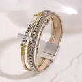Detailed view of bohemian multilayer bracelet with BLESSED cross charm and magnetic clasp - Gold