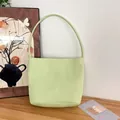 Detailansicht einer minimalistischen hellgrünen Nylon-Schultertasche auf Holz. - Senfgrün [mit Schriftzug - Verdickter Boden] / Kleine Größe - Wenden Sie Sich An Den Kundenservice Wenn Sie Eine Version Ohne Schriftzug Benötigen.