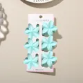 Set of six light blue plumeria flower hair claw clips on white display card stand - 4cm Frangipani Style / 6-Piece Set / Matte Light Blue / Bulk Packaging