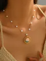 Close-up van een vergulde ketting met zonnehanger en witte parels op een model - Parel Zon Golf Stijl (SN20210852)