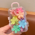 Close-up view of colorful flower hair claw clips stored inside a cute mini suitcase box. - Flower Style