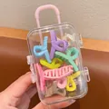 Close-up of colorful mini hair claw clips inside a cute mini suitcase storage box - Crisscross Style