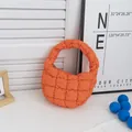 Primer plano de un bolso de nube acolchado naranja vibrante con suave relleno de algodón - Naranja