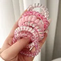 Close-up view of various pink and patterned spiral hair ties held by a hand in detail - OPP Bag Style / Pink