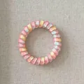 Macro view of a colorful gradient pink and yellow spiral telephone wire hair tie - Standard / Peach Red Gradient