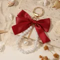 Elegant red satin bow keychain featuring faux pearl accents on a warm beach background. - Burgundy (ZJ16873)