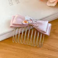 Detaillierte Nahaufnahme eines eleganten Haarkamms mit rosa Satinschleife und Strasssteinen - Haarnadel - Strass-Stil / Rosa