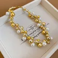 Detailed close-up of a fashion pearl and gold bead necklace in a white wooden jewelry box - White Faux Pearl / Gold