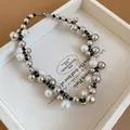 Detail of a multi-layered pearl necklace with silver beads in a white wooden tray. - Black Beaded / Silver
