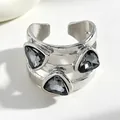Primo piano di un anello aperto argento con tre pietre nere a forma di triangolo. - Anello (0065) / 1 Pezzo / Argento