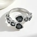 Primo piano di un anello color argento con diverse pietre nere a forma di cuore - Anello (0068) / 1 Pezzo / Argento
