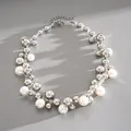 Detailed macro shot of a pearl and silver bead clustered necklace on textured gray leather - Silver-White