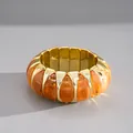 Detailopname van een vintage armband van oranje gemarmerd acryl en goud metaal - Ovale Schakel Armband / koffiekleur