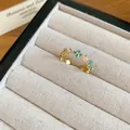 Détail d'une bague ouverte plaquée or 18 carats avec fleurs bleues et perles. - Bague ouverte trèfle / Or-Bleu