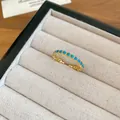 Gros plan d'une bague plaquée or 18k avec zircons turquoise dans un écrin à bijoux - Bague Ouverte en Pierre Bleue-Verte / Or-Bleu