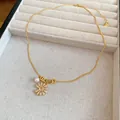 Détail d'un collier plaqué or 18 carats avec fleur en zircon et pendentif en perle - Collier / Collier Or
