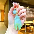 Elegant iridescent translucent green crab claw keychain with blue charm held in hand - Gold Hardware Electroplated Crab Claw / Aurora Green