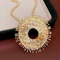 Gros plan détaillé d'un collier pendentif soleil doré élégant avec strass et motif d'abeille - Collier / Or