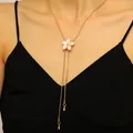 Detailed view of an elegant gold flower lariat necklace worn on a black V-neck dress - Enamel Flower Style (4090) / White