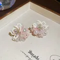 Détail rapproché de boucles d'oreilles fleurs en perles roses et blanches sur plateau beige - Aiguille Argentée N° 5 - Blanche - Rose