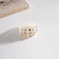 Detailed macro view of a chunky cream resin ring with sparkling inlaid rhinestones - Ring / Beige