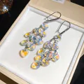 Close-up of iridescent heart-shaped crystal tassel earrings with zircon studs in jewelry box. - AB Color