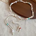 Detail van een bohemian gevlochten tailleketting met kleurrijke kralen en schelpaccenten - Wit