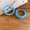 Primer plano de pendientes de aro de esmalte azul claro con textura única sobre madera - Tops / Azul