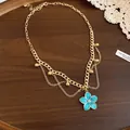 Detail view of a gold-plated chain necklace featuring a vibrant blue enamel flower pendant - Necklace / Blue