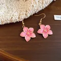 Close-up of pink enamel flower drop earrings with gold-tone finish on a cozy background. - Earring Hooks / Pink