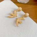Elegant matte gold swallow bird stud earrings featuring a unique hammered texture - Swallow Drop Earrings / Gold