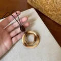 Macro detail of resin bamboo-style double ring pendant necklace on canvas background. - Bamboo Texture Double Ring Pendant Style (6)