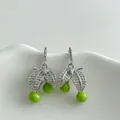 Close-up of green cherry earrings with sparkling zirconia leaves on a white stand. - Silver Earring Post-Green