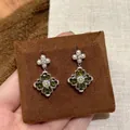 Close-up of sparkling green zircon flower earrings on brown fabric stand - Vintage Floral Style (23#) / Silver / Silver-Green