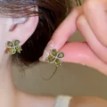 Close-up of sparkling green zircon flower stud earrings shown on ear and held by hand. - 39# Flower Stud Earrings / Silver-Green