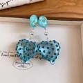 Close-up view of blue heart-shaped resin earrings with sparkling blue rhinestones - Silver Post Style / Blue