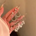 Detail view of sparkly long crystal tassel earrings with pearl and teardrop beads - Silver/White