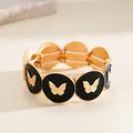 Détail d'un bracelet gothique rétro en acrylique avec breloques papillon dorées et noir. - Bracelet - Motif Papillon / Or-Noir