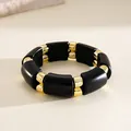 Gros plan d'un bracelet en acrylique noir et or avec des blocs épissés au style rétro sombre - Bracelet - Patchwork Incurvé / Or-Noir