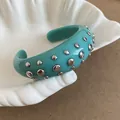 Detailed macro view of a teal resin cuff bracelet with polished silver metal studs on a shell - Style 55
