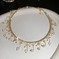 Makro-Detail eines eleganten Vintage-Gold-Chokers mit Kristallfransen und Glanzeffekten - Halsband-Gold-Weiß