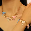 Detailed close-up showing the colorful enamel bow pendants on gold necklace and bracelet - Bracelet + Necklace / Gold