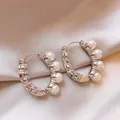 Detailed view of silver C-shaped hoop earrings with pearls and sparkling crystals. - Silver